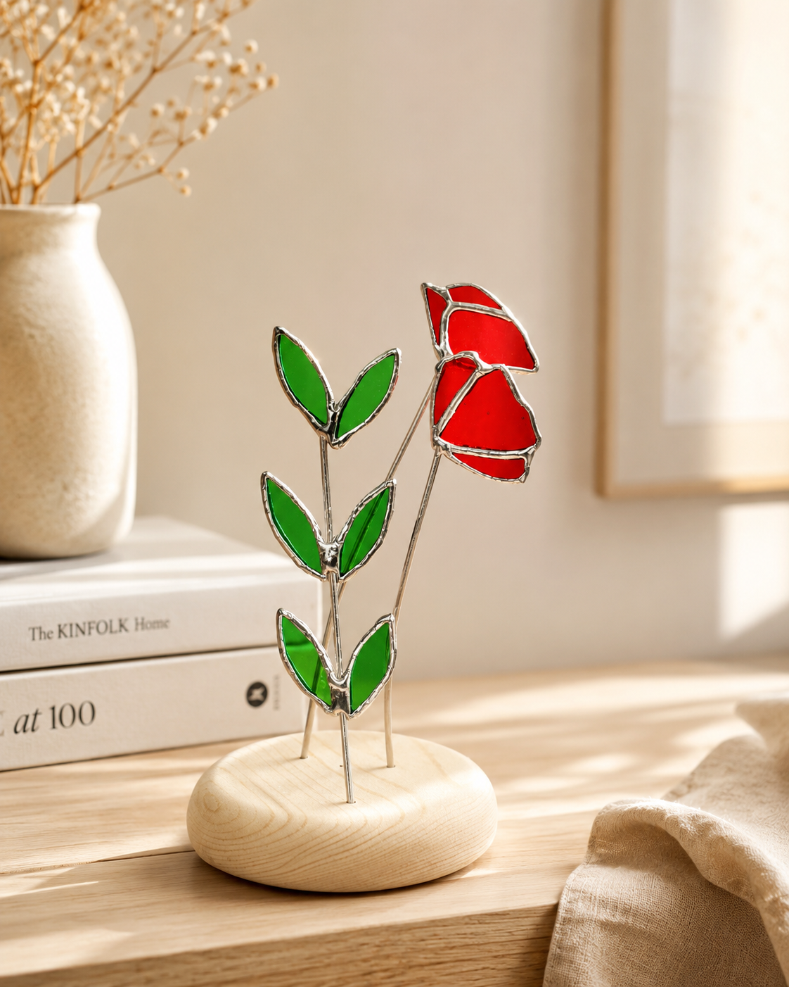 گل دکوراتیو شیشه‌ای دست‌ساز طرح شقایق قرمز با برگ‌های سبز و پایه چوبی